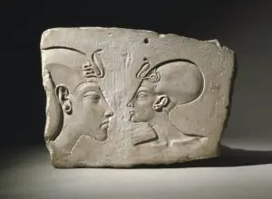 Head of a king (left), maybe Akhenaten with a khat headdress and a royal uraeus. With him is Queen Nefertiti wearing cap crown with a uraeus too.